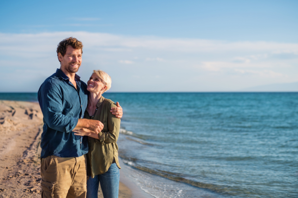 A young couple standing outdoors on beach, talking. Copy space.