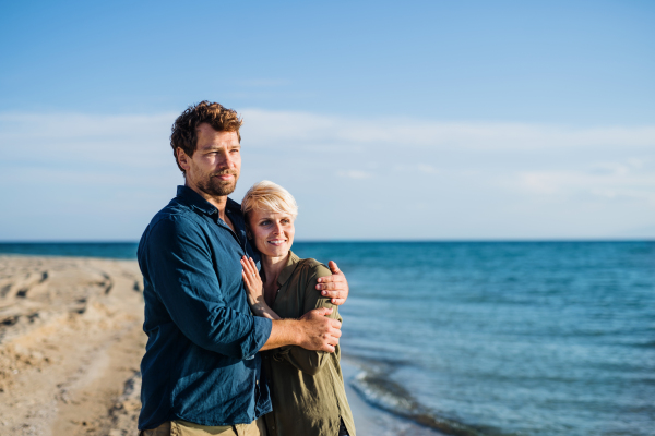 A young couple standing outdoors on beach, talking. Copy space.