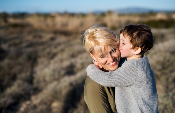 Young mother with small daughter standing in mediterranean nature, kissing.