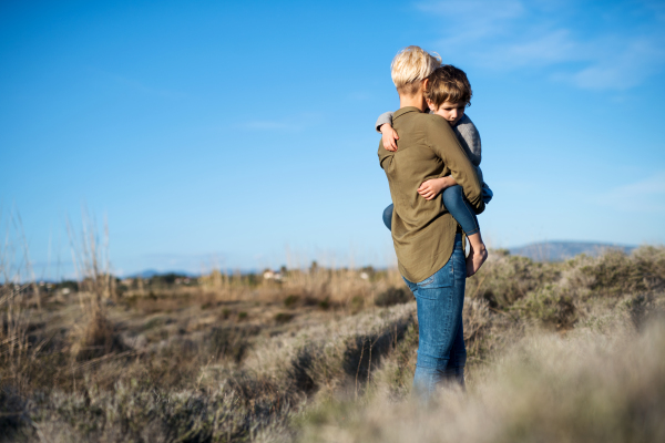 Young mother with small daughter walking in mediterranean nature, holding her.