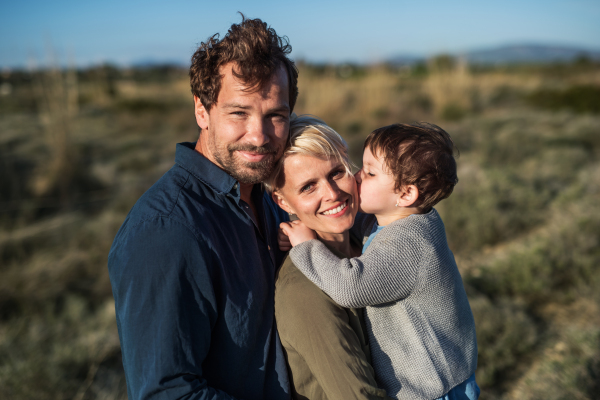 A portrait of young family with a small daughter standing outdoors in nature in Greece.