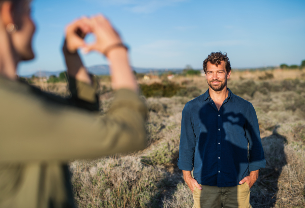 A young happy affectionate couple standing outdoors in olive orchard.