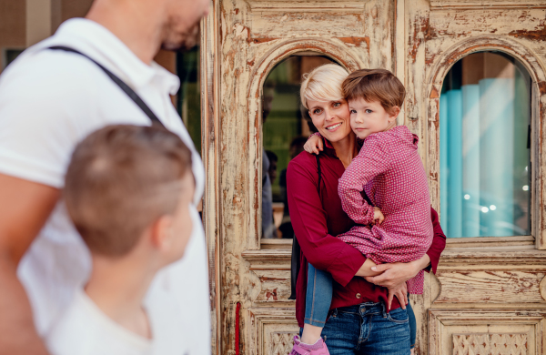 A midsection of young family with two small children walking outdoors in town.