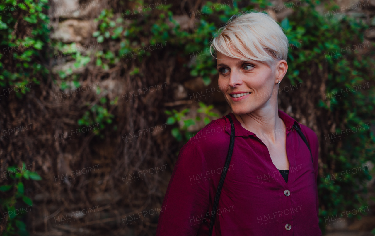 A portrait of blond woman standing outdoors, looking away. Copy space.