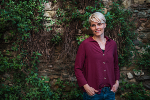 A portrait of blond woman standing outdoors, looking at camera. Copy space.