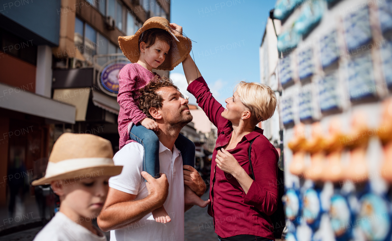 Happy young family with two small children standing outdoors in town on holiday.