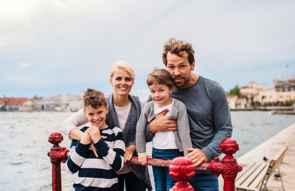 A portrait of young family with two small children outdoors on beach, looking at camera.