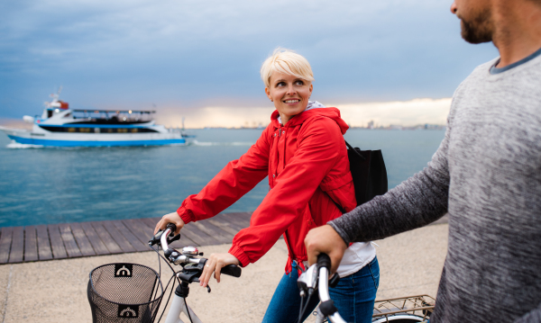 Happy couple with bicycles outdoors on beach, talking.