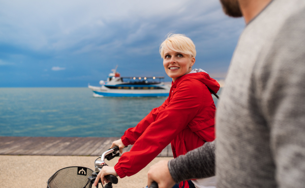 Happy couple with bicycles outdoors on beach, talking. A midsection.