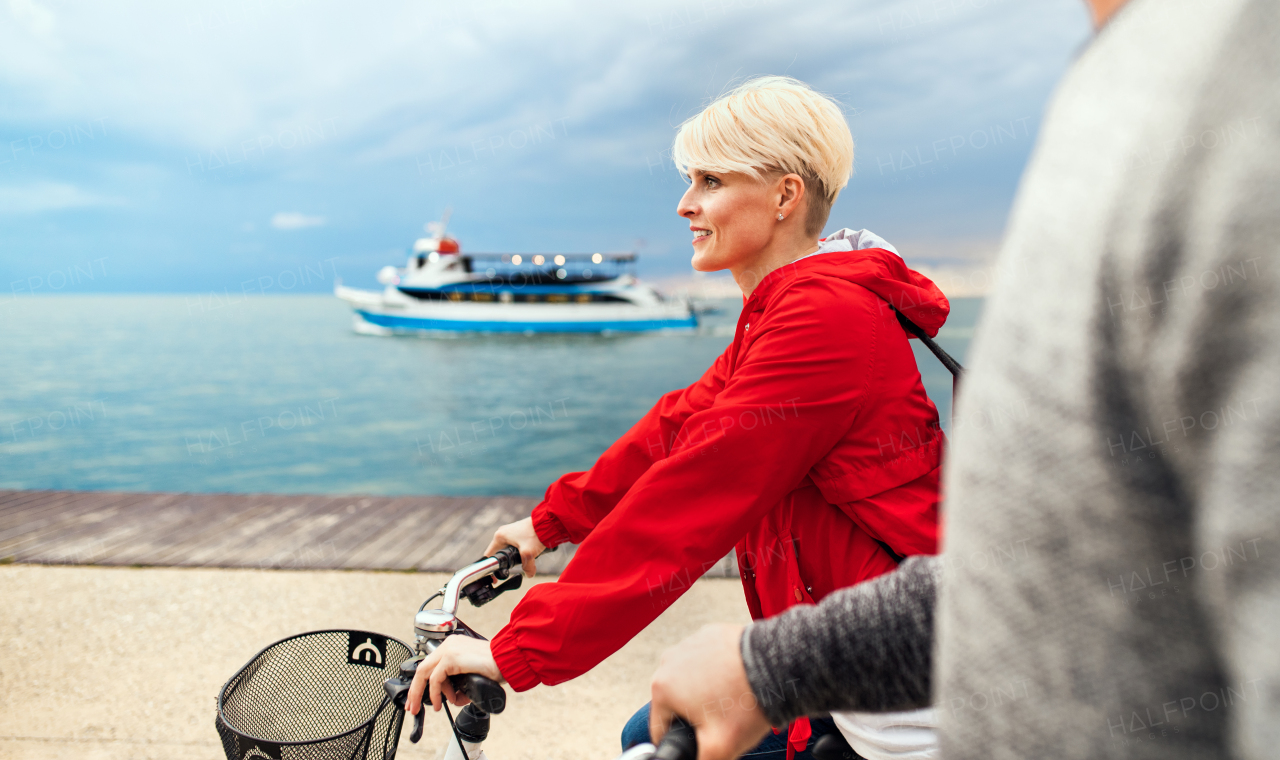 A midsection of young couple with bicycles cycling outdoors on beach.