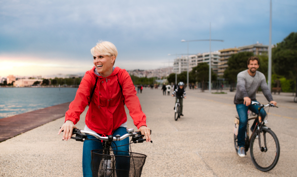 Young happy family riding bicycles outdoors on beach.