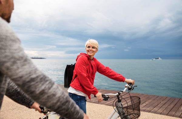 Happy couple with bicycles outdoors on beach, talking. A midsection.