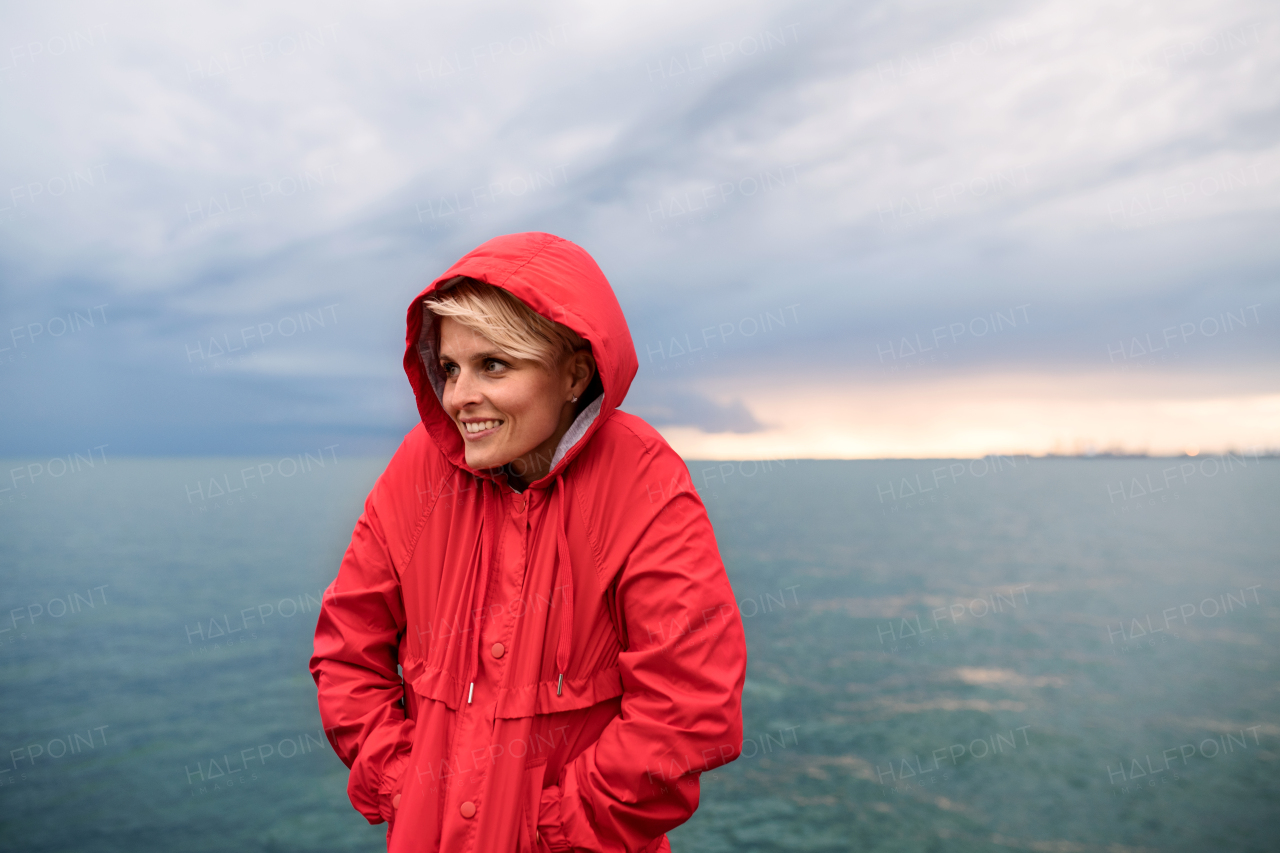 A portrait of young woman standing outdoors on beach at dusk. Copy space.