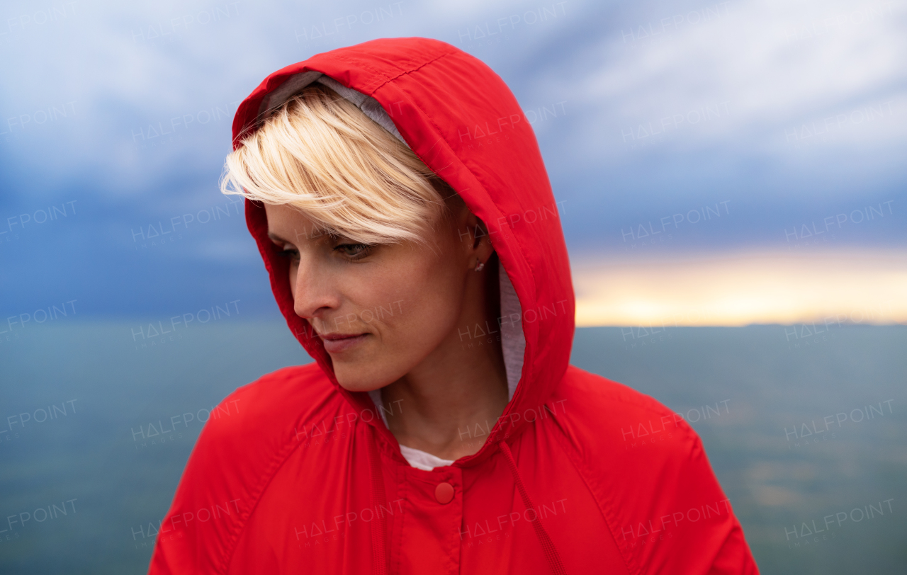 A portrait of young woman standing outdoors on beach at dusk.