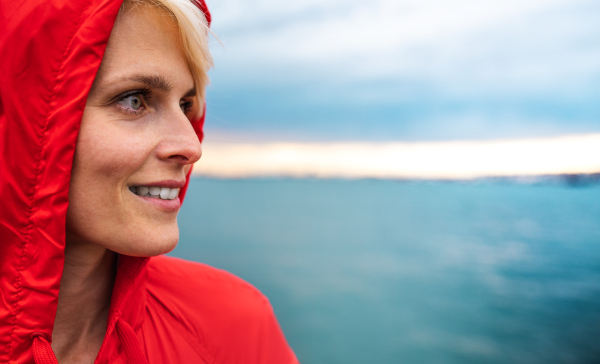 A portrait of young woman standing outdoors on beach at dusk. Copy space.