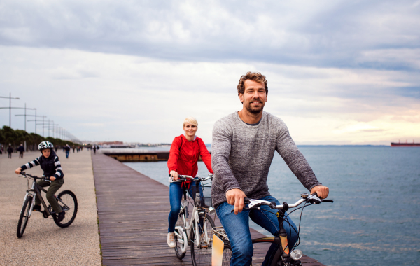 Young happy family riding bicycles outdoors on beach.