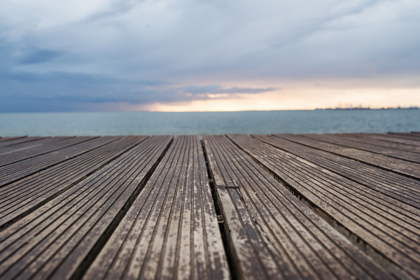 A view of wooden decking, sea and gray sky at dusk.