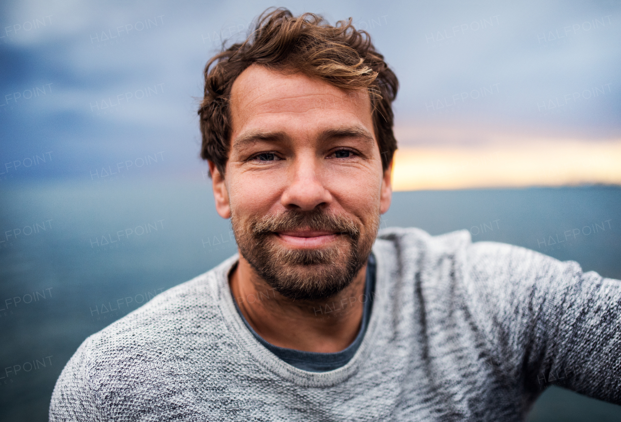 A portrait of happy handsome man standing outdoors, looking at camera.