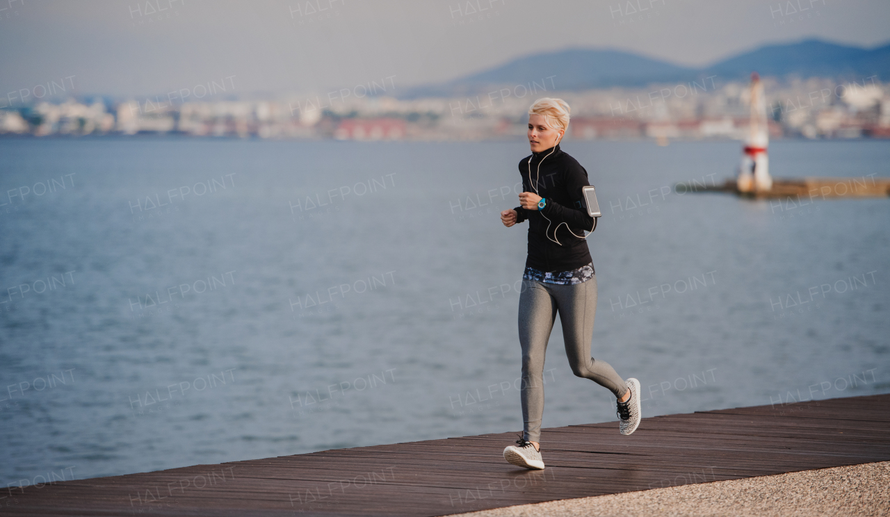 Side view of young sportswoman running outdoors on beach. Copy space.