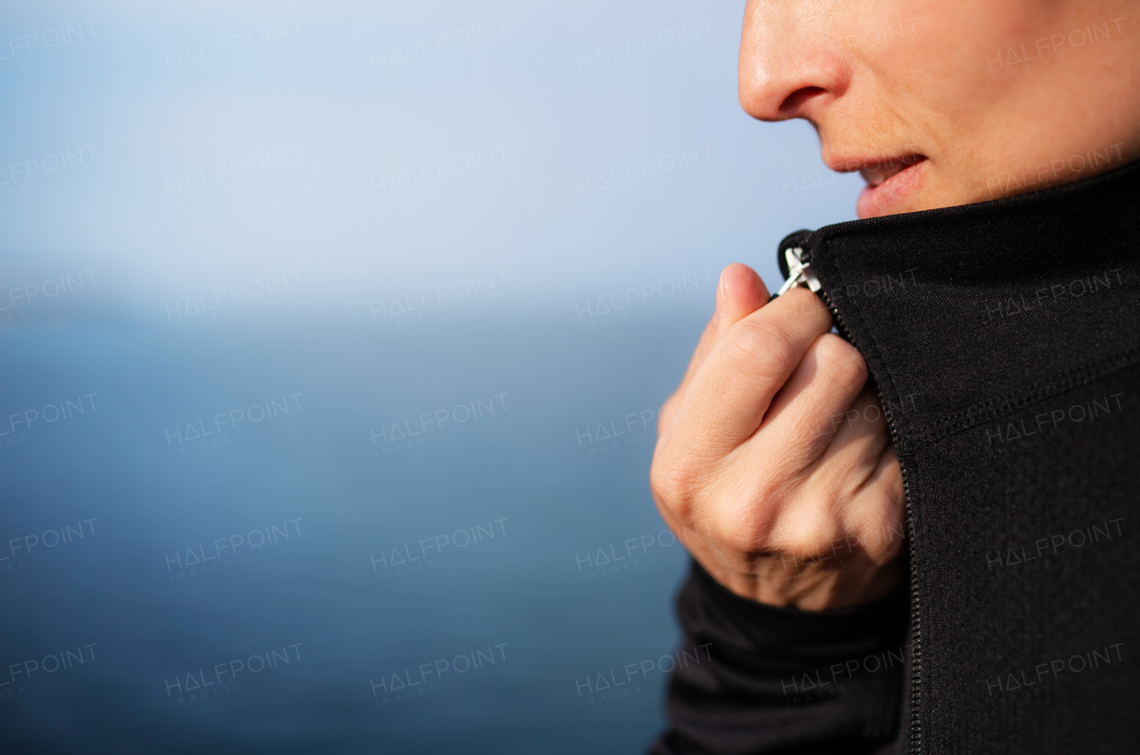 Midsection of young sportswoman standing outdoors on beach, close-up.