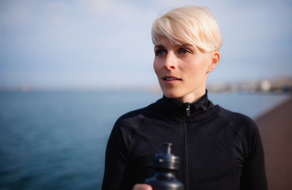 A portrait of young sportswoman resting after doing exercise outdoors. Copy space.