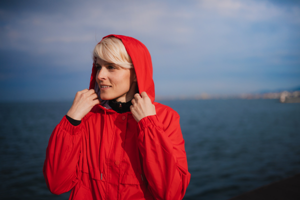 Front view portrait of young sportswoman standing outdoors on beach, resting.