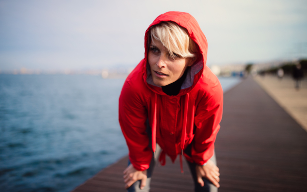 Front view portrait of young sportswoman standing outdoors on beach, resting.