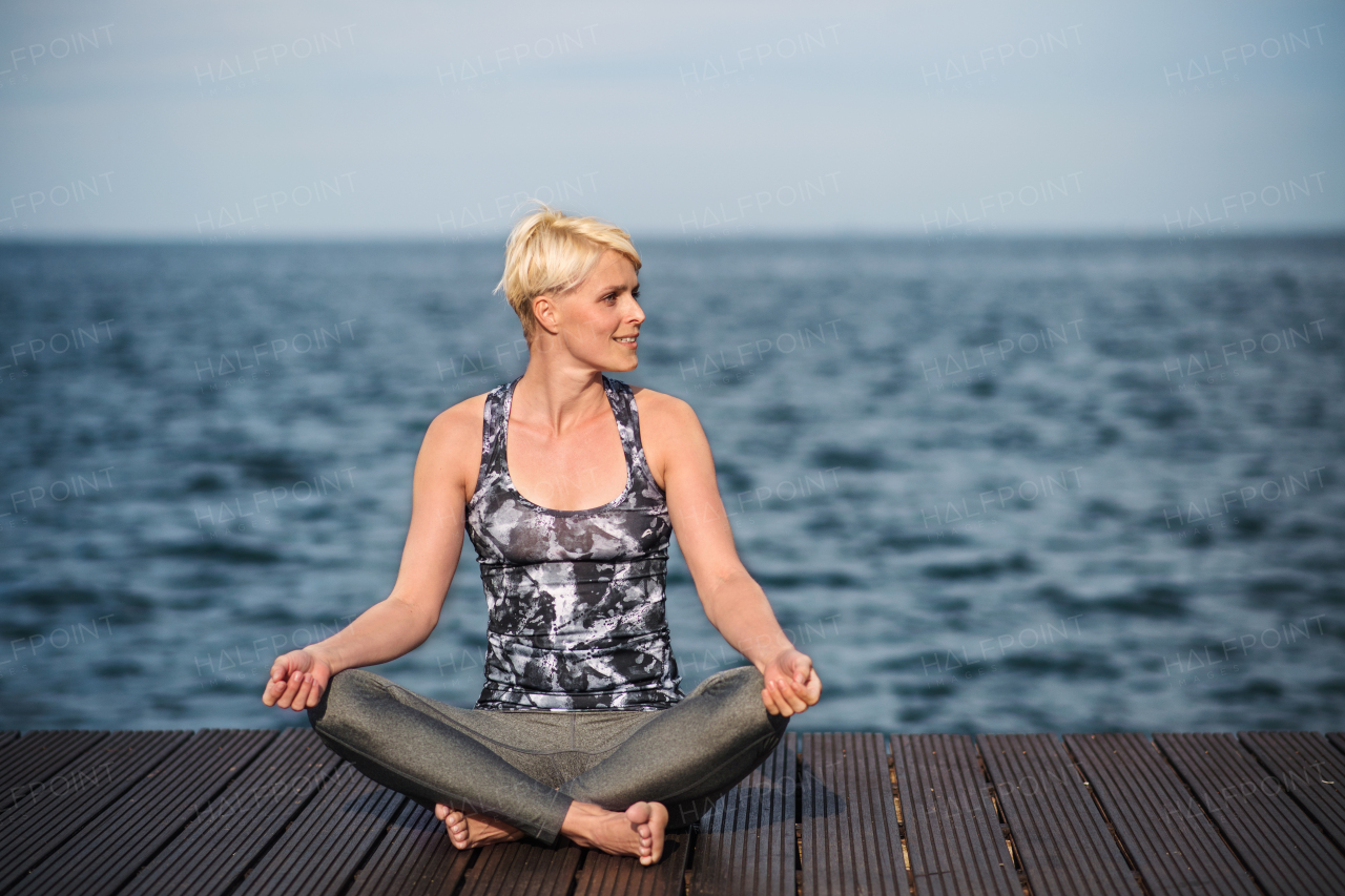 Front view portrait of young sportswoman doing yoga exercise on beach. Copy space.