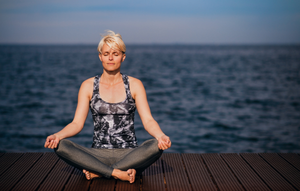 Front view portrait of young sportswoman doing yoga exercise on beach. Copy space.