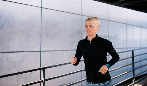 A young sportswoman doing exercise outdoors in city, running.