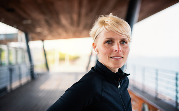 A portrait of young sportswoman resting after doing exercise outdoors. Copy space.