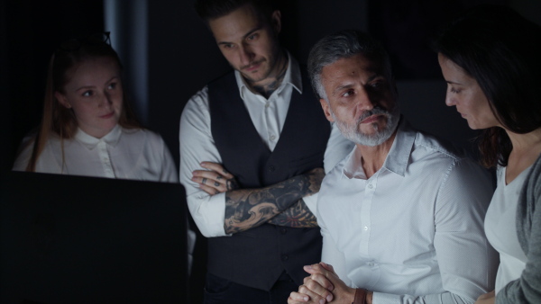 A group of businesspeople with computer indoors in office, discussing issues.