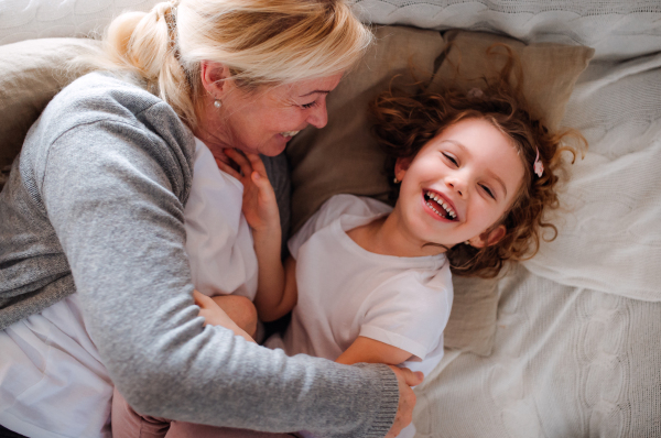 A top view portrait of small girl with grandmother having fun at home. Copy space.