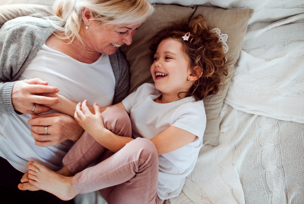 A top view of portrait of small girl with grandmother having fun at home. Copy space.