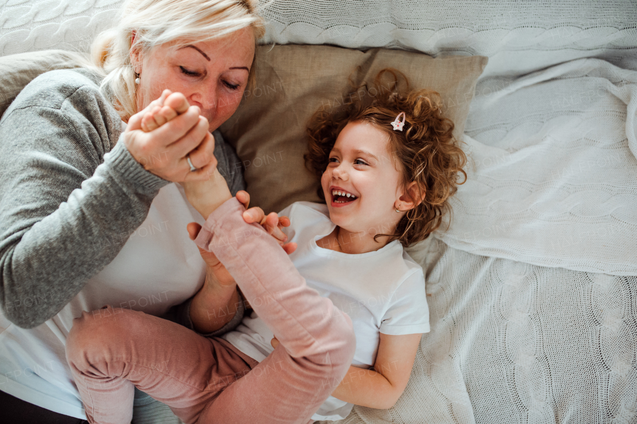 A portrait of small girl with grandmother having fun at home. Copy space.