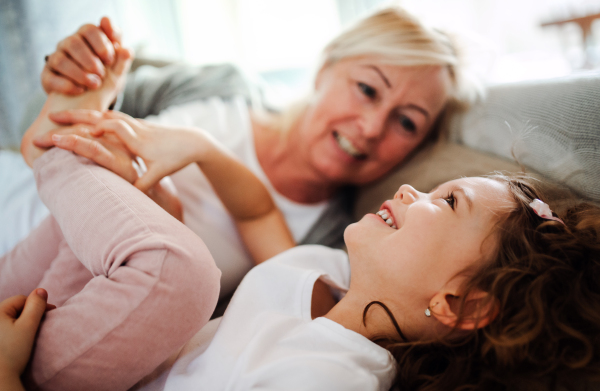 A portrait of small girl with grandmother having fun at home. Copy space.