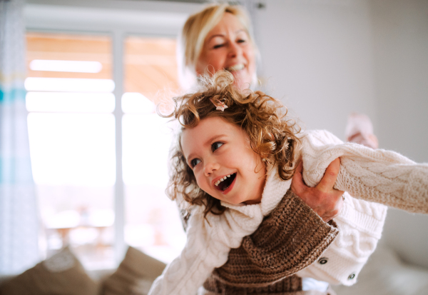 A portrait of small girl with grandmother having fun at home. Copy space.