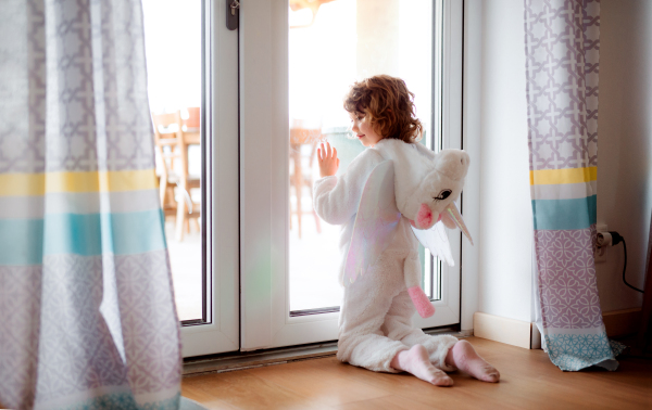 A happy small girl in unicorn mask playing at home.