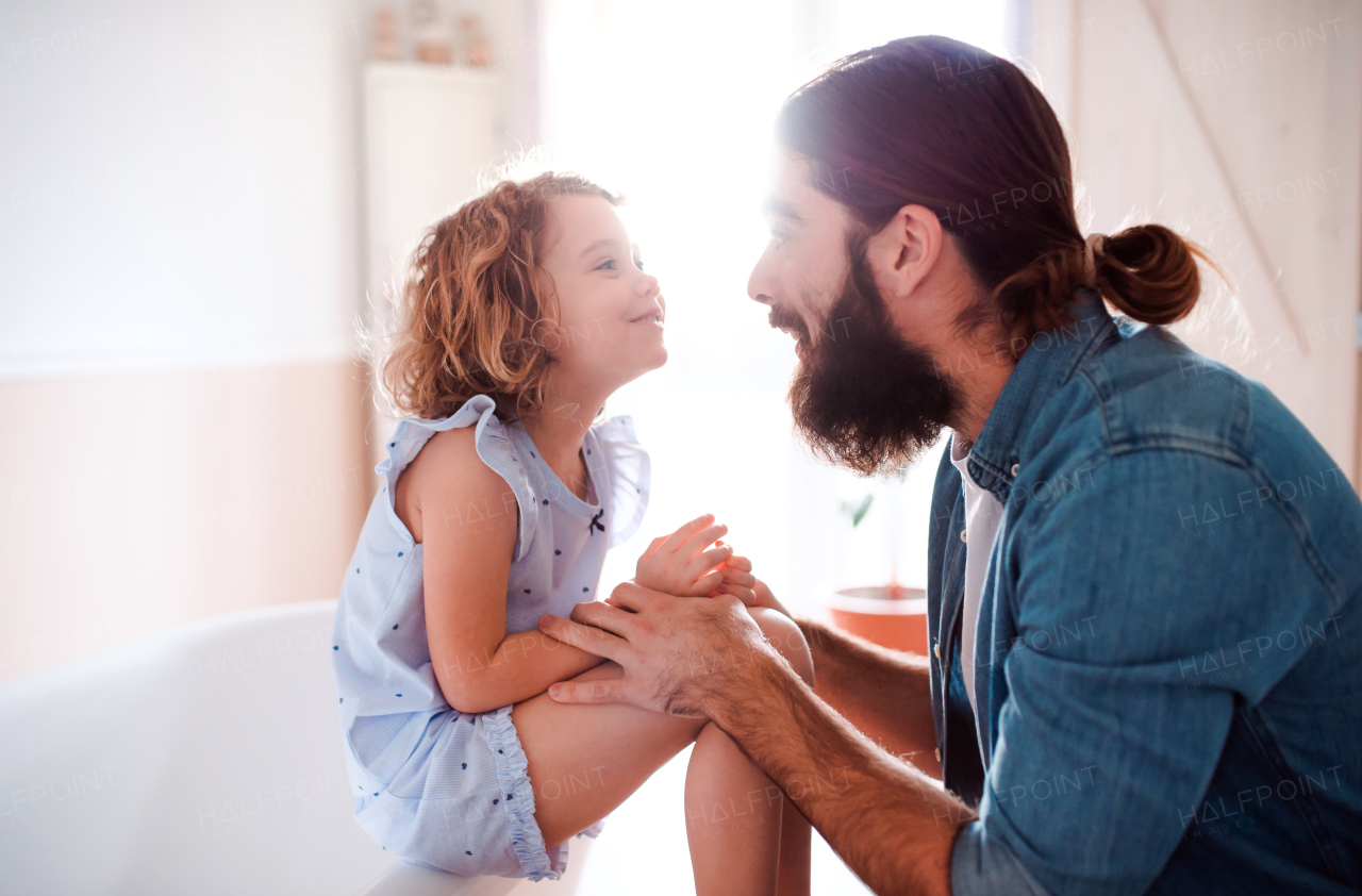 A cute small girl with young father at home, talking.