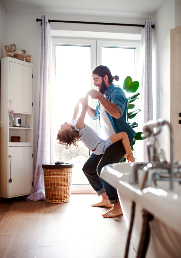 A small girl with young father in bathroom at home, having fun.