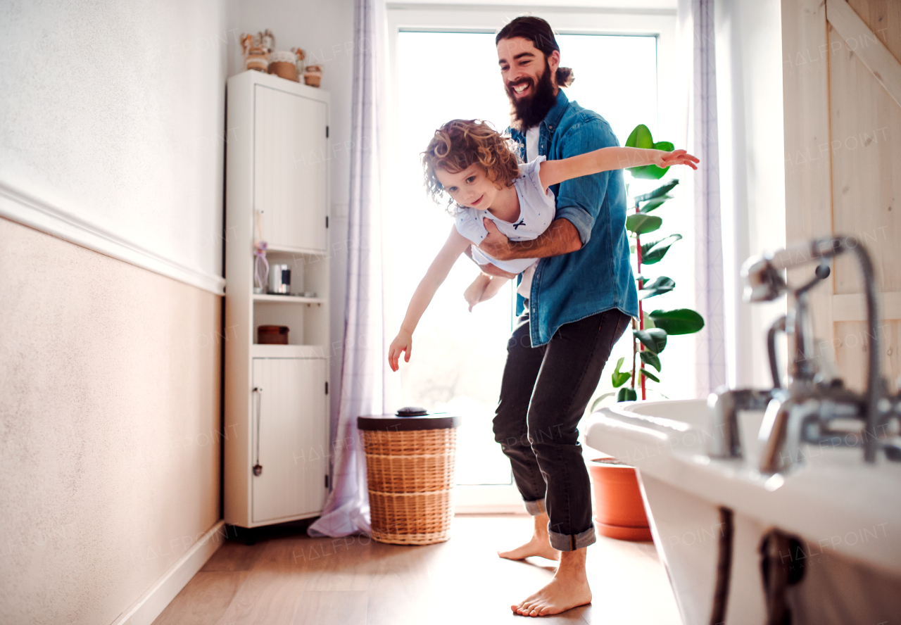 A small girl with young father in bathroom at home, having fun.