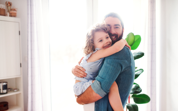 A cute small girl with young father at home, hugging.