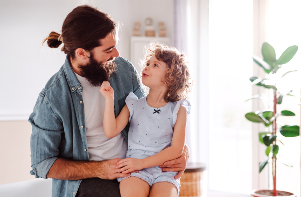 A cute small girl with young father at home, talking. Copy space.