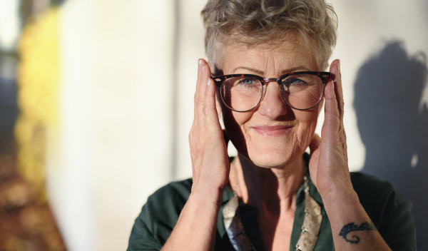 A portrait of senior woman standing outdoors in town, looking at camera.