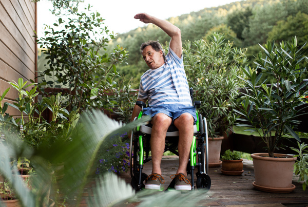 A senior man in wheelchair doing exercise on terrace.