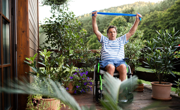 A senior man in wheelchair doing exercise on terrace.