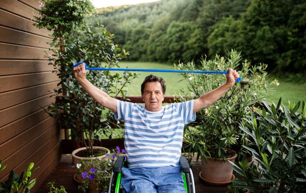 A senior man in wheelchair doing exercise on terrace.