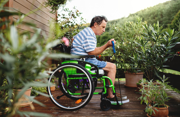 Side view of senior man in wheelchair doing exercise on terrace.