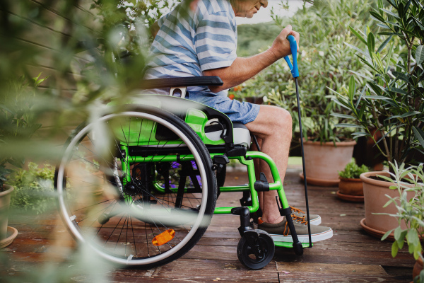 An unrecognizable senior man in wheelchair doing exercise on terrace.