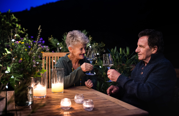 Happy senior couple drinking wine in the evening on terrace.